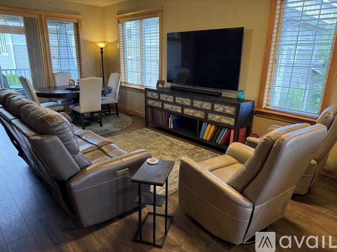 A living room with a television, leather chairs, and a coffee table.