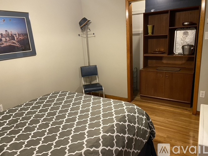 A bedroom with a patterned bedspread and a wooden cabinet.