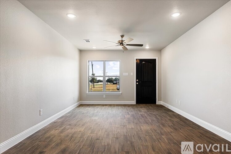 A spacious room with a ceiling fan and a view of the outdoors through a large window.