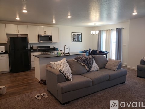 A living room with a grey couch and a kitchen in the background.