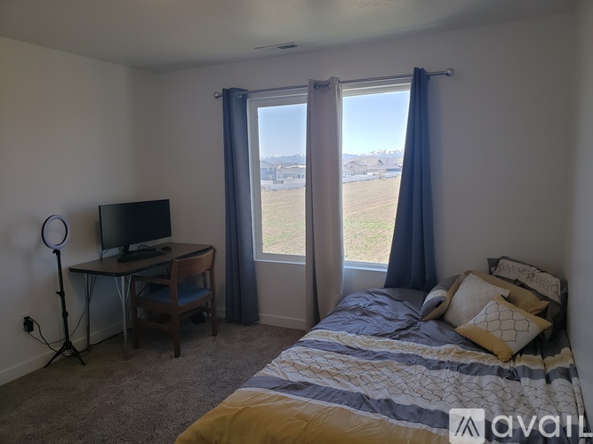 A bedroom with a bed, desk, chair, and a window with a view of the outdoors.