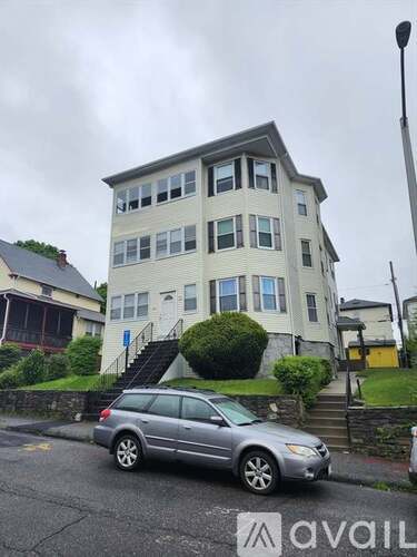 A silver car is parked in front of a two-story building.