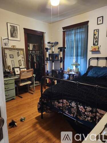 A bedroom with a bed, desk, chair, and clothing rack.