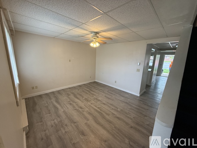 A room with a ceiling fan and light fixture, and a wooden floor.