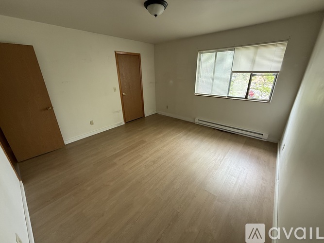 A room with wooden flooring and a window with blinds.