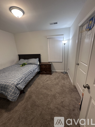 A bedroom with a bed, nightstand, and window with blinds.