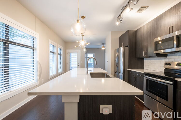 A modern kitchen with a long white island in the middle.