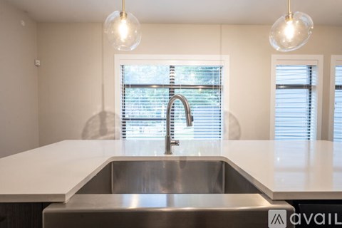 A modern kitchen with a stainless steel sink and white countertops.