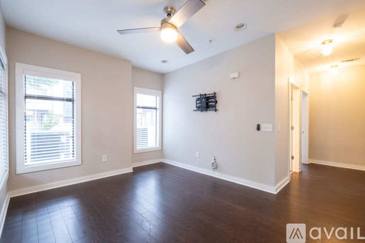 A spacious room with a ceiling fan and hardwood flooring.