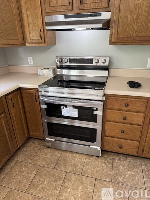 A kitchen with a stainless steel oven and wooden cabinets.