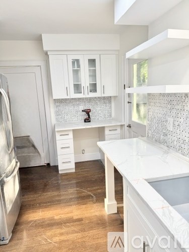 A kitchen with white cabinets and a wooden floor.