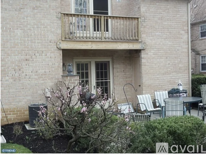 A balcony with a table and chairs is on the second floor of a brick building.