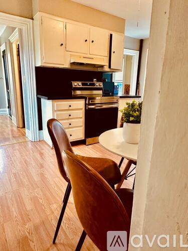 A kitchen with a wooden floor and a white table with a chair.