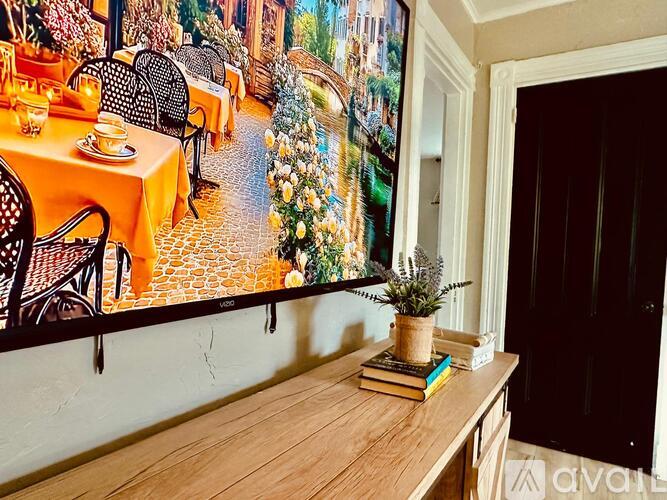 A dining area with a table set for two and a large picture on the wall.