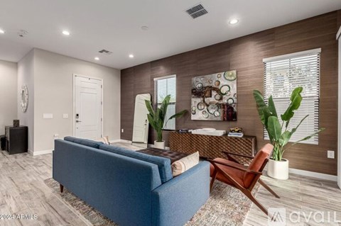 A living room with a blue couch, a brown chair, and a large painting on the wall.