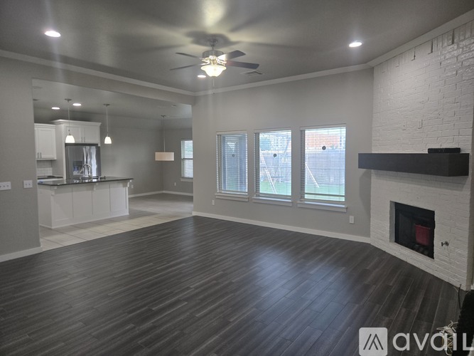 A spacious living room with a fireplace and a ceiling fan.