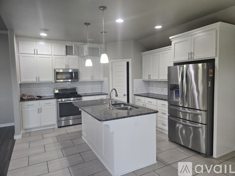 A modern kitchen with white cabinets and stainless steel appliances.