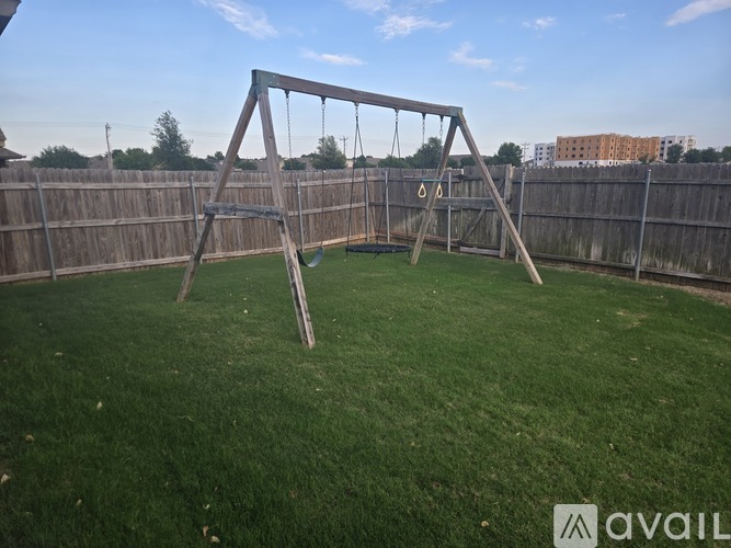 A wooden swing set sits in a grassy backyard.