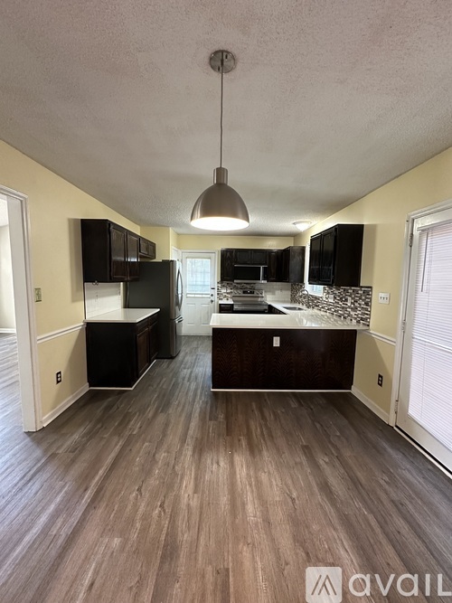 A kitchen with black cabinets and a wooden floor.