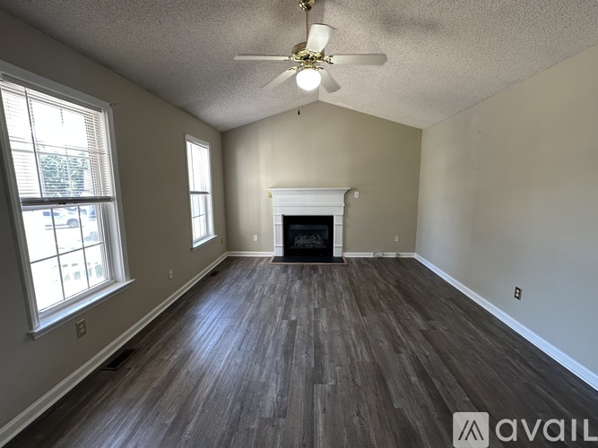 A spacious room with wood flooring and a fireplace.