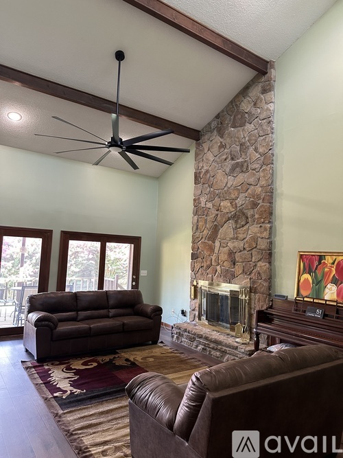 A living room with a brown leather couch and a stone fireplace.