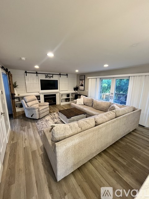 A living room with a large couch and a flat screen TV mounted on the wall.