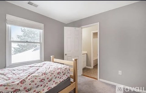 A bedroom with a bed, a window, and a door.