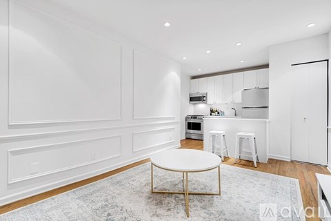 A modern kitchen with white cabinets and a round table in the center.