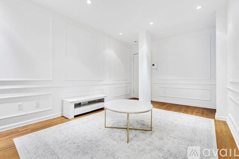 A white room with a round table and a white bench.