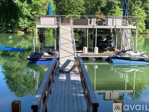 A wooden dock leads to a houseboat on a calm lake.
