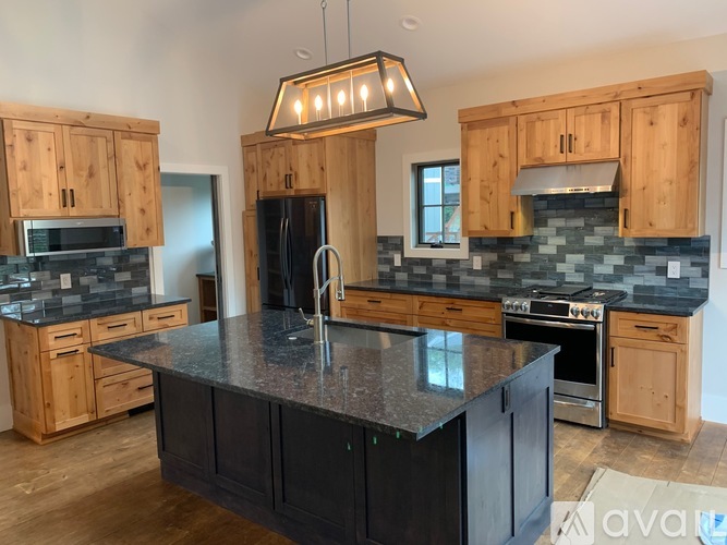 A kitchen with wooden cabinets and a black island.