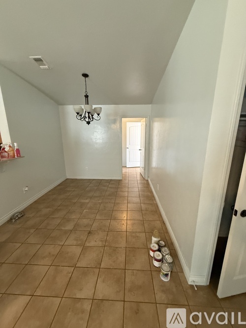 A room with a chandelier and a door at the end.