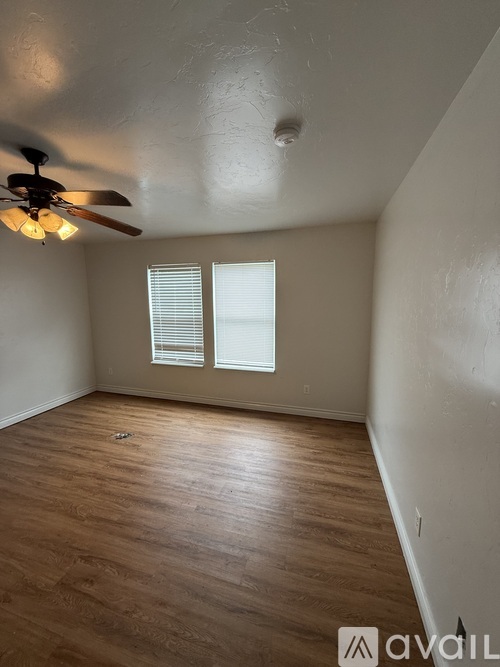 A room with a ceiling fan and wooden flooring.