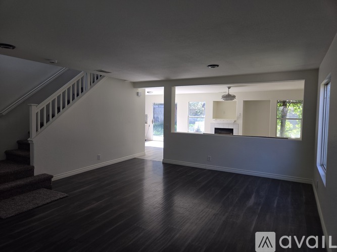 A spacious room with wooden floors and a staircase leading to another level.
