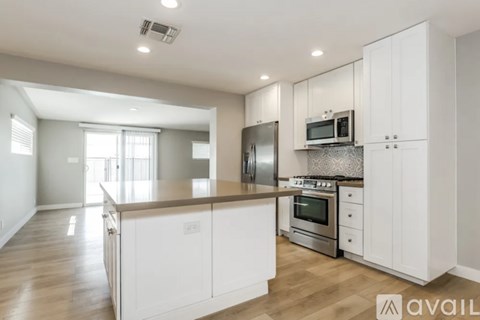 A modern kitchen with white cabinets and stainless steel appliances.