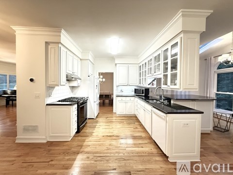 A spacious kitchen with white cabinets and black countertops.