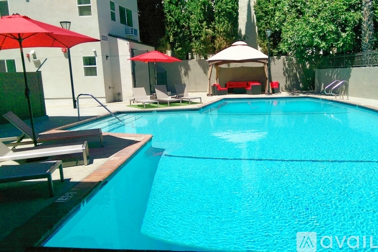 A pool with a red umbrella and a gazebo.
