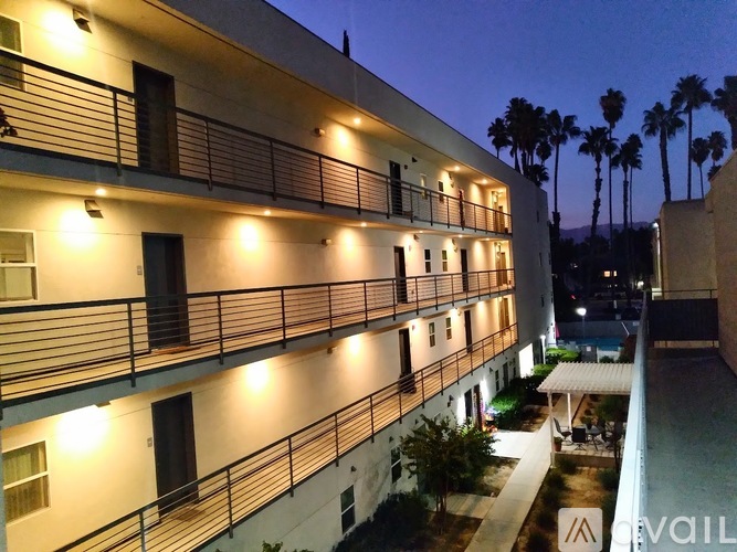 A building with balconies and palm trees in the background.