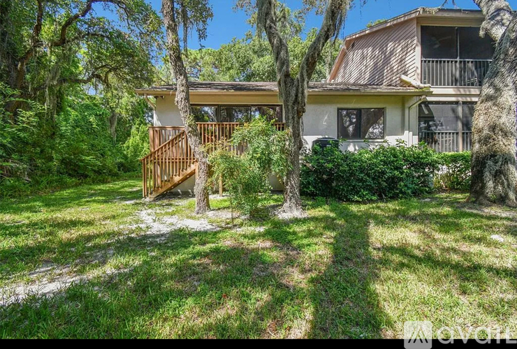 A house with a wooden deck and trees in front.