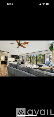 A modern living room with a grey sofa and a ceiling fan.