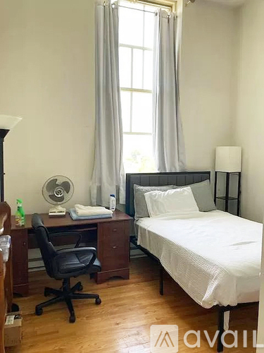 A bedroom with a bed, desk, and chair.
