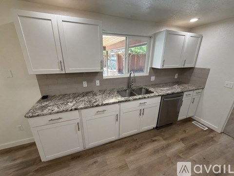 A kitchen with white cabinets and a granite countertop.