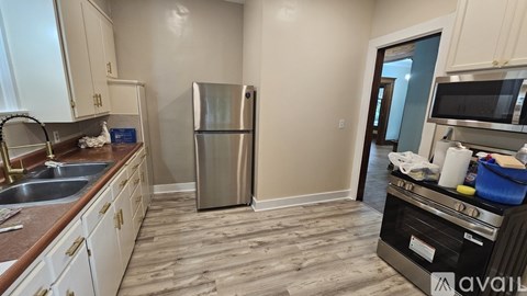A kitchen with a refrigerator, sink, and stove top oven.