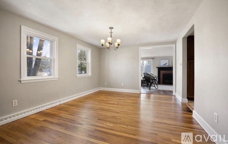 A spacious room with wooden floors and a fireplace.