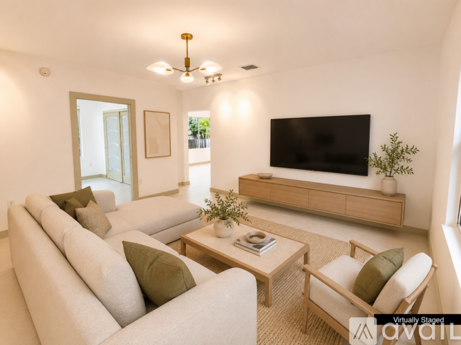 A living room with a white couch, a wooden coffee table, and a flat screen TV mounted on the wall.