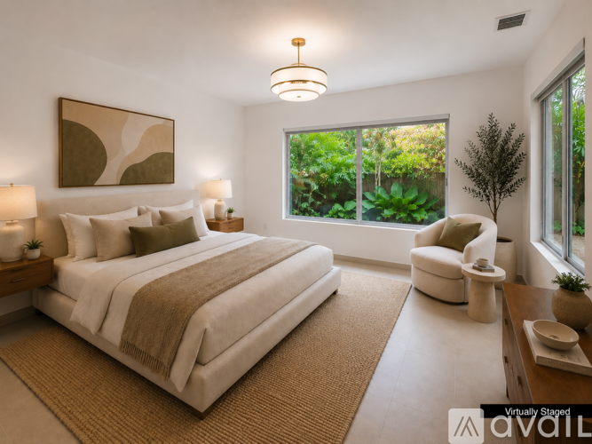 A bedroom with a large bed and a window overlooking greenery.