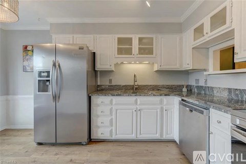 A kitchen with a stainless steel refrigerator and white cabinets.