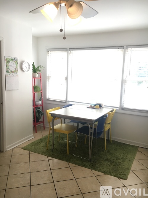A room with a table and chairs and a fan.