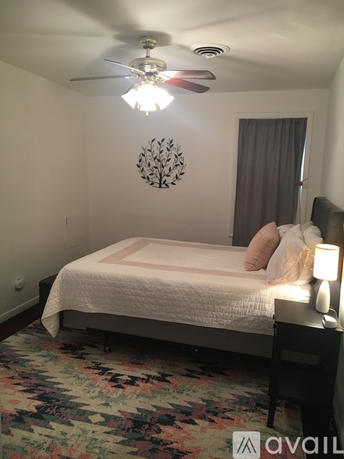 A bedroom with a bed, a ceiling fan, and a floral rug.