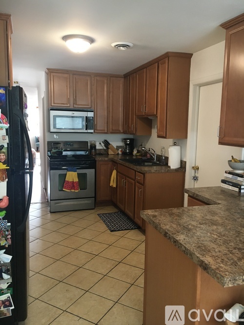 A kitchen with brown cabinets and a black refrigerator.